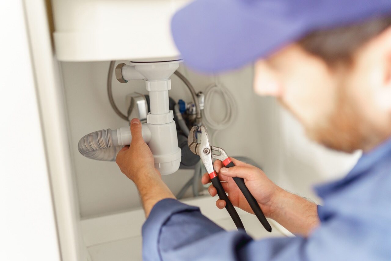 Close up of handyman installs a siphon pipe on the kitchen sink. High quality photo