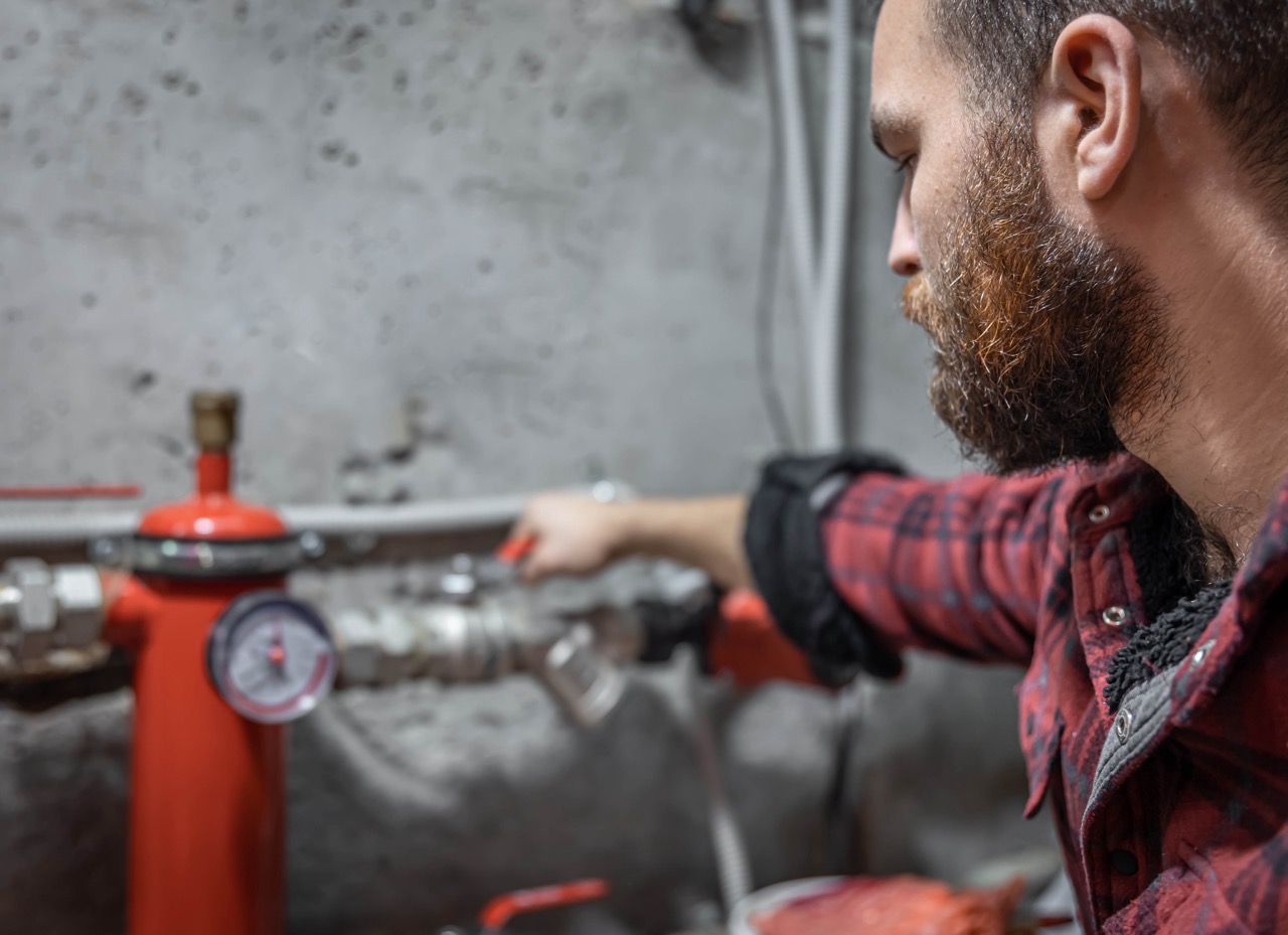 The man looks at the expansion tank, faucet, pipes, valve, pressure meter, copy space.