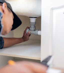 Engineering, plumbing and man fixing pipes by a sink for repairs or maintenance at a house. Profess.