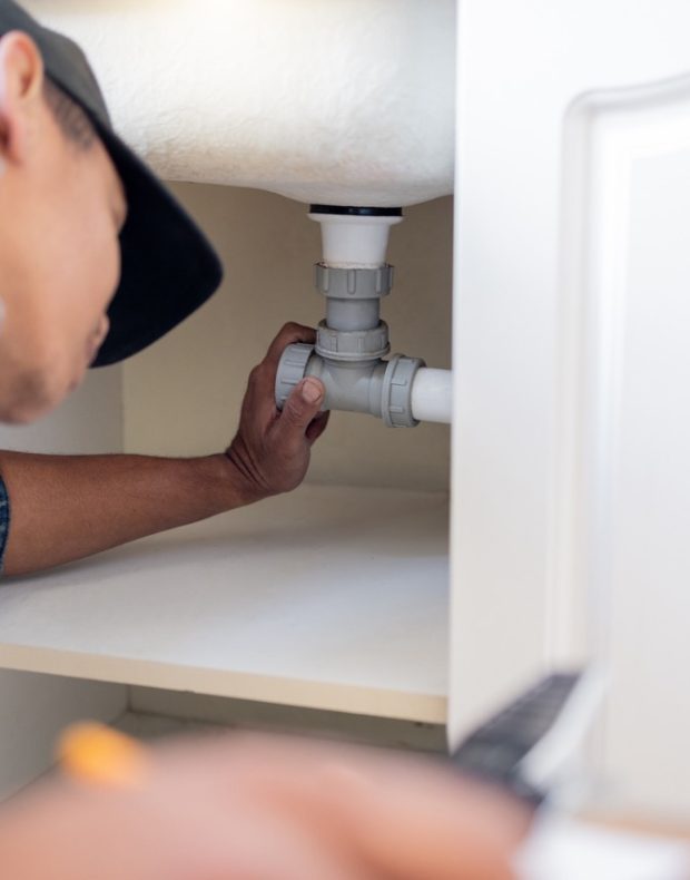 Engineering, plumbing and man fixing pipes by a sink for repairs or maintenance at a house. Profess.